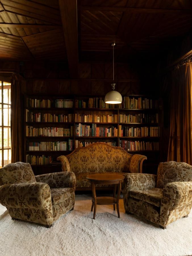Regał pełen książek, sofa i dwa fotele w drewnianym wnętrzu
