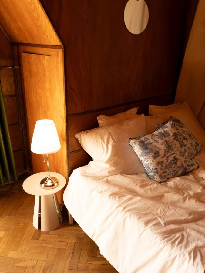 Łóżko z białą pościelą i zapalona lampka nocna w drewnianej sypialni